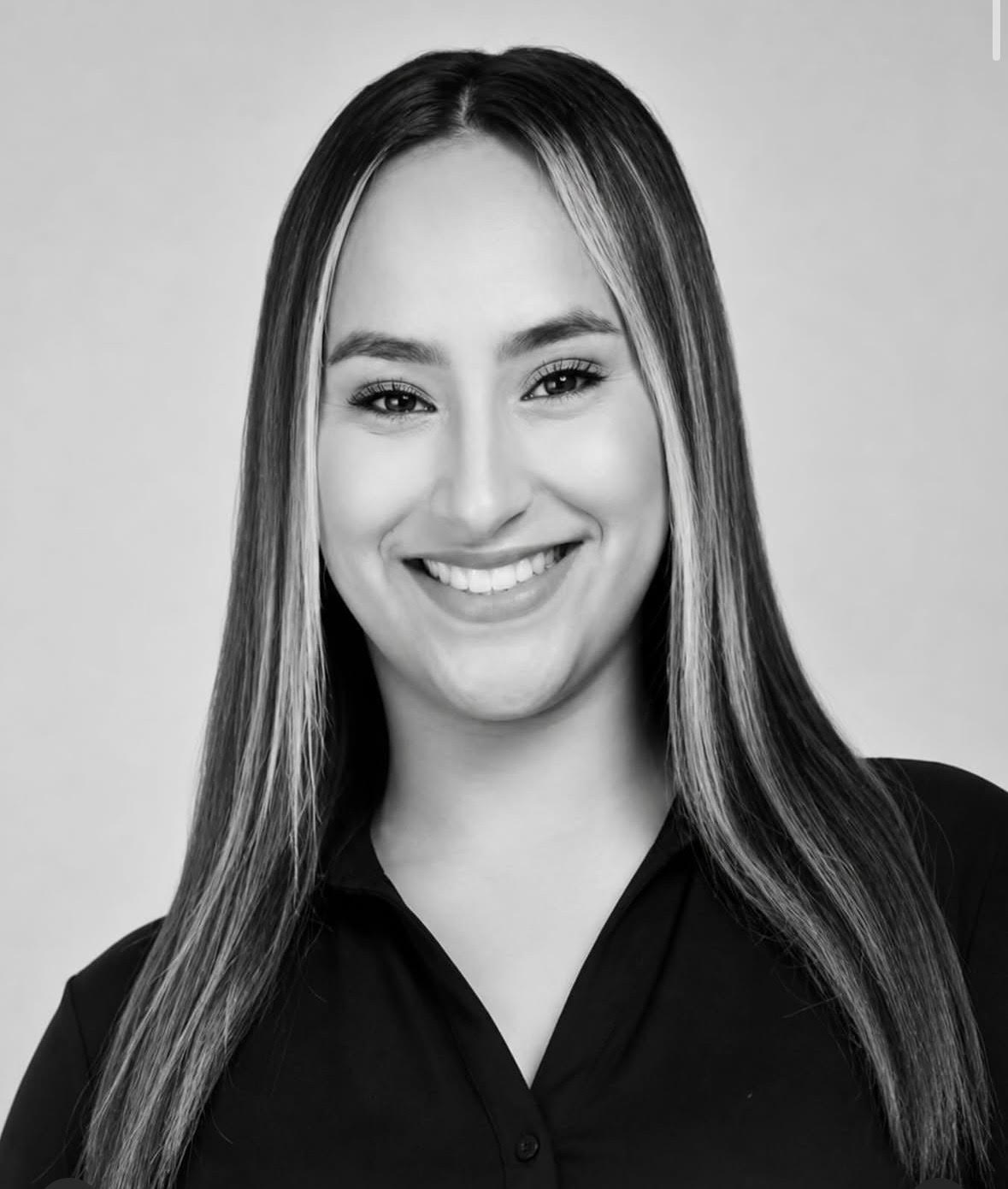 Portrait of Lexis Hernandez smiling in a black shirt against a light background